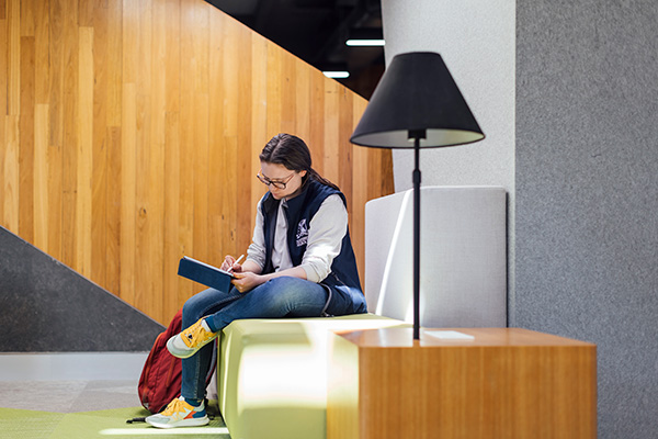 Female student sits on a seat in a common area in the Melbourne Veterinary School