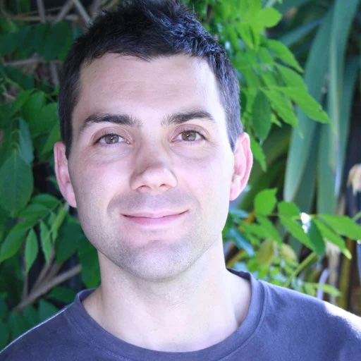 Aaron Jex, standing in front of verdant leaves